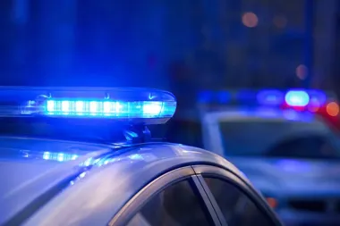 Zbliżenie na niebieskie światła policyjnego radiowozu nocą, w tle rozmyty drugi radiowóz.